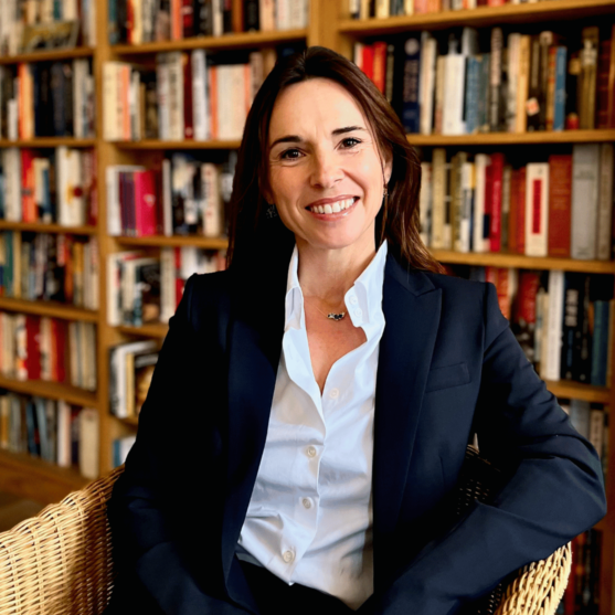 Tessa Willmott, leading coach, sitting in front of a book case